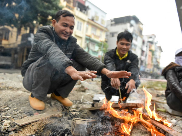 Người dân Hà Nội đốt củi sưởi ấm trên đường trong ngày mưa rét