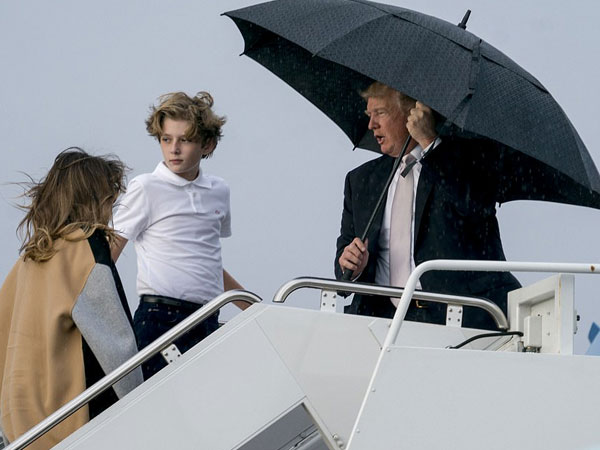 Ông Trump cầm ô đi trước vợ con giữa trời mưa