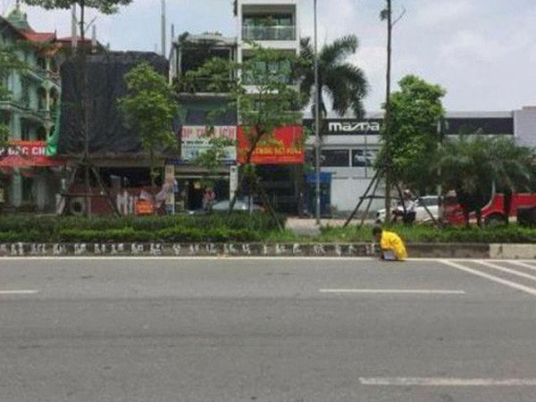 Người đàn ông mặc áo vàng in hình rồng phượng viết hàng loạt 'chữ lạ' trên vỉa hè Hà Nội