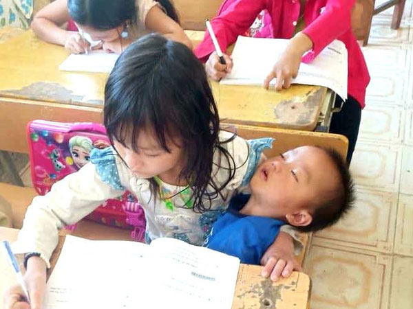 Dân mạng xúc động với bức ảnh cô trò nhỏ miền cao: Tay bế em trai đang ngủ, tay say sưa viết bài