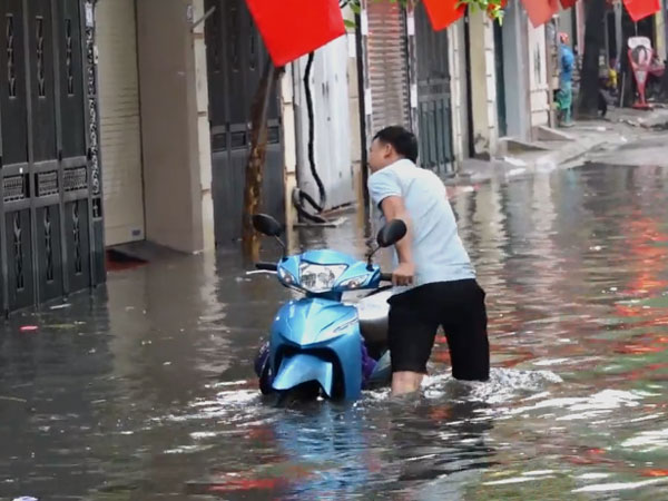 Người dân ở Hà Nội bì bõm trên phố sau cơn mưa lớn