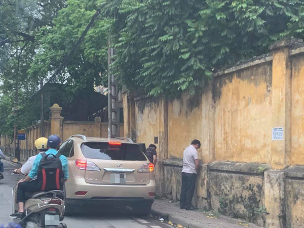 Hình ảnh 2 quý ông đứng tiểu bậy ngay cạnh xe Lexus đậu bên đường Hà Nội khiến nhiều người bức xúc