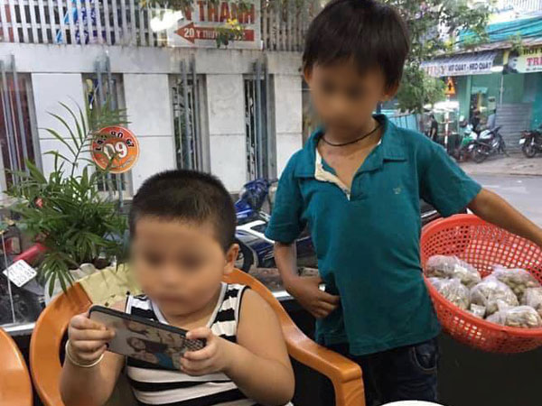1 bức ảnh, 2 số phận: Hình ảnh cậu bé bán hàng rong lặng lẽ 'xem ké' điện thoại của người bạn cùng tuổi bên bàn lẩu khiến nhiều người xót xa