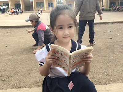 Cô bé tiểu học ở Đắc Lắk gây sốt với bức ảnh ngồi đọc truyện ở sân trường