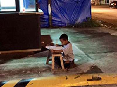 Cậu bé vô gia cư dùng ánh đèn lọt ra từ cửa hàng McDonald's để học bài