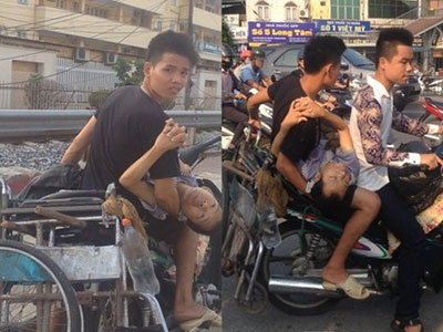 Hai thanh niên đầu trần bế theo người tàn tật lao xe vun vút