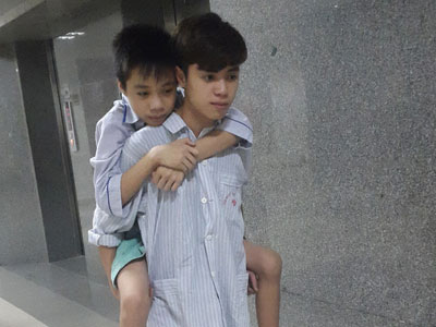 Đau lòng cảnh hai anh em mồ côi cha cõng nhau đi viện