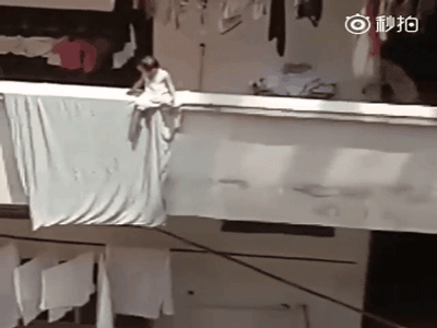 Thót tim cảnh bé gái ngồi vắt vẻo ở ban công trên cao cha mẹ không hay biết