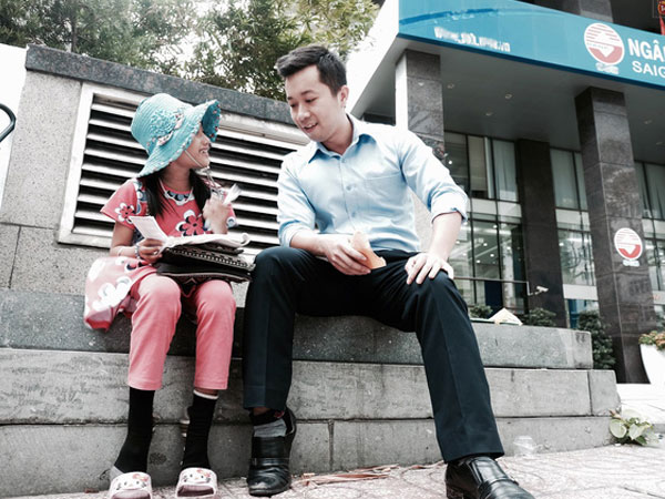Anh nhân viên ngân hàng dành giờ nghỉ trưa mỗi ngày để dạy chữ cho cô bé vé số ngay trên vỉa hè Sài Gòn