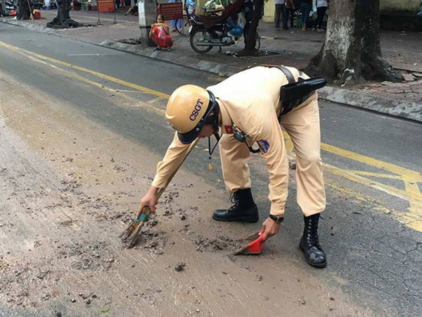 CSGT Hà Nội dừng xe thu dọn bùn đất vương vãi trên đường