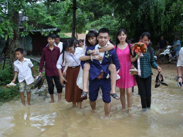 Đám cưới mùa mưa bão: Chú rể hạnh phúc cõng cô dâu qua đoạn đường ngập nước và bùn đất