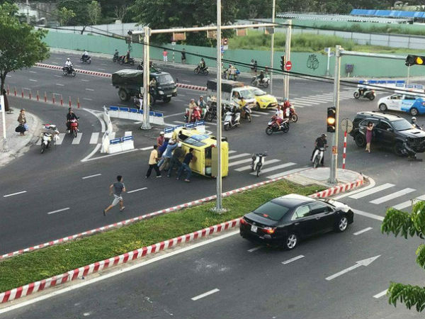 Taxi lật giữa giao lộ, người đi đường hợp sức cứu tài xế bị mắc kẹt
